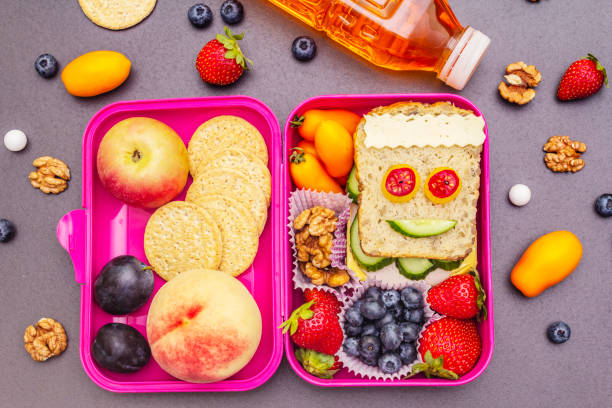 School lunch box School lunch box with sandwich, fresh fruits, vegetables, cookies, juice and nuts. Healthy eating habits for kids. Back to school concept. Black stone concrete background, top view, close up walnut cookies stock pictures, royalty-free photos & images
