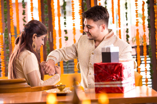 Brother and sister celebrating Raksha Bandhan Woman tying rakhi on her brother's wrist on the occasion of Raksha Bandhan festival rakhi stock pictures, royalty-free photos & images