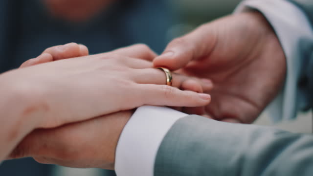 Cropped hands of couple exchanging wedding rings