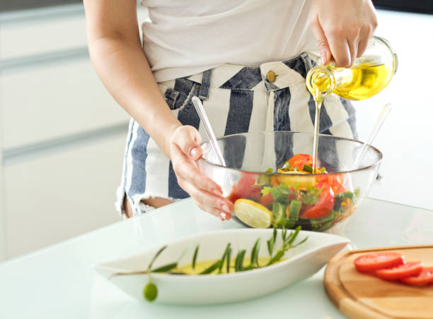 gesundes essen, vegetarisches essen, diät und menschen konzept-aus der nähe der jungen frau dressing pflanzlichen salat mit olivenöl zu hause - dressing room women female adult stock-fotos und bilder