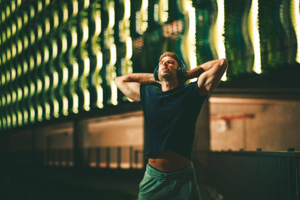 istock Young sports man taking a break and stretching arms and back during a night jogging 1171771504
