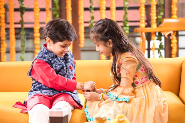 Girl and boy celebrating Raksha Bandhan festival Girl tying rakhi on her brother's wrist on the occasion of Raksha Bandhan festival rakhi stock pictures, royalty-free photos & images