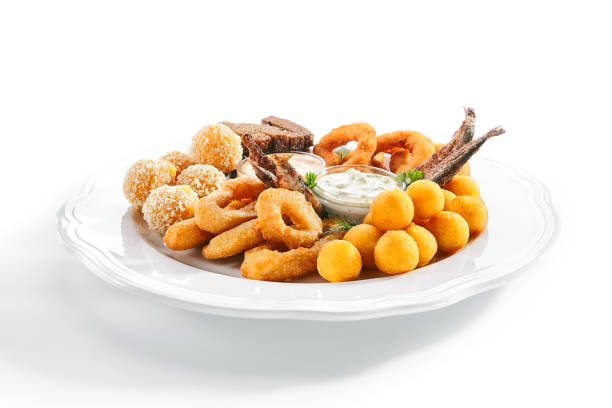 Beer snacks or beer plate with fried onion rings, squid rings, crisp cheese balls, potato croquettes, garlic croutons, deep-fried smelt fish with tartar sauces and a thousand islands dressing
