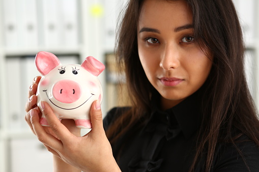 young beautiful brunette woman hold piggybank in arms