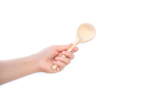 istock Female hand holds a wooden spoon on a white background 1171778456