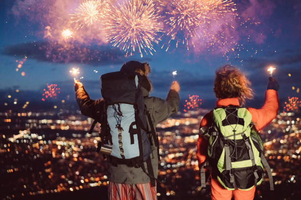 Couple celebrating New Year on the mountain top Couple with burning sparklers against the night cityscape new year urban scene horizontal people stock pictures, royalty-free photos & images