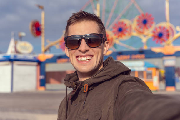 istock man taking a selfie in coney island. Luna park as background 1171785256