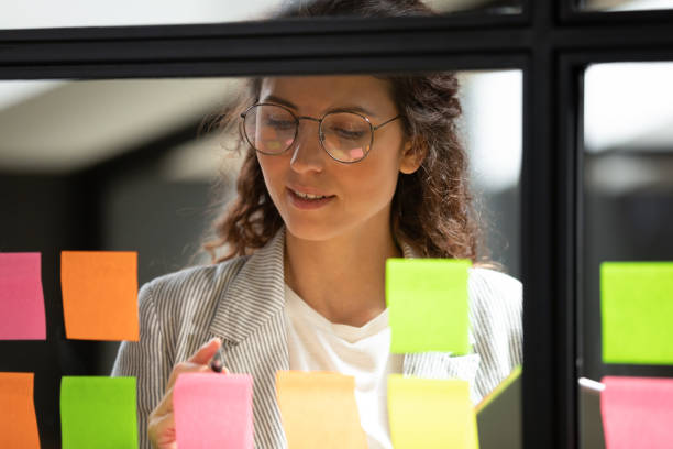 istock Young businesswoman write ideas on sticky notes on glass board 1171786273