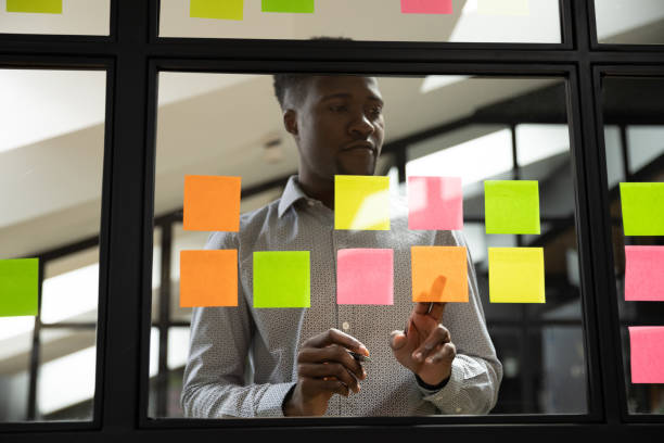istock Serious african businessman write ideas on sticky notes on glass 1171786283