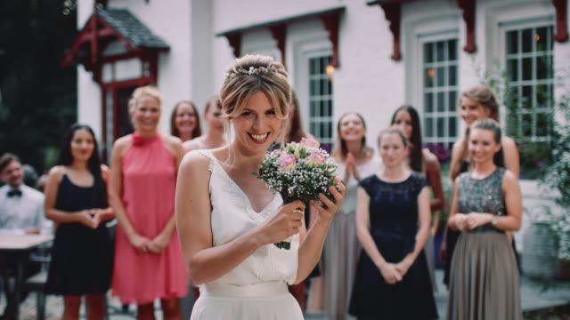 Happy bride throwing bouquet to wedding guests