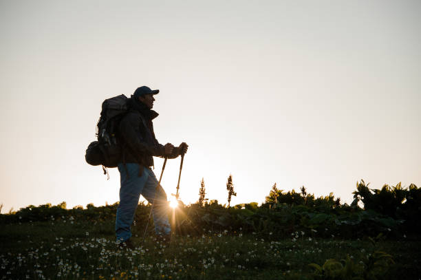 istock Man standing on the hill field with hiking backpack and sticks 1171787309
