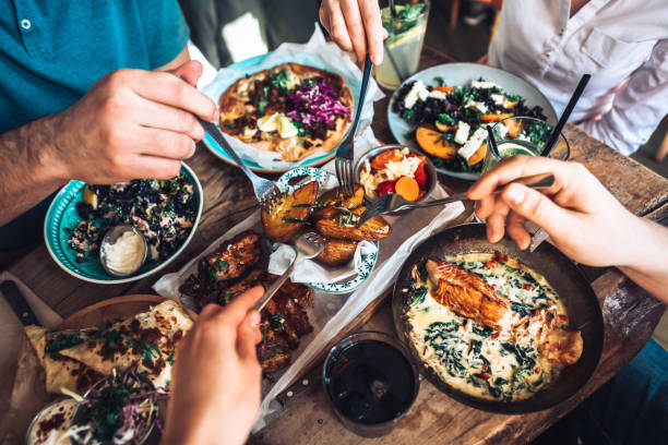 godersi il pranzo con gli amici - dining table people foods and drinks restaurant foto e immagini stock