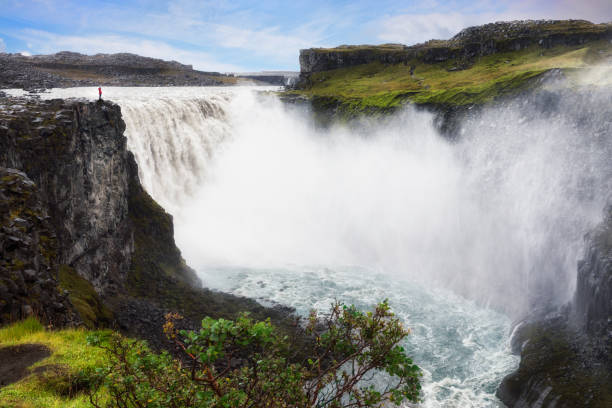 dettifoss, islandia con una pequeña figura de pie en el acantilado - large waterfall fotografías e imágenes de stock