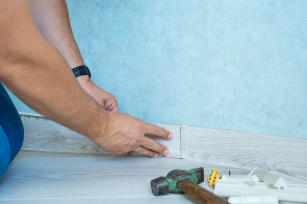 istock Worker's hands Instal plastic skirting board on laminate flooring. Renovation of baseboard at home. 1171789084