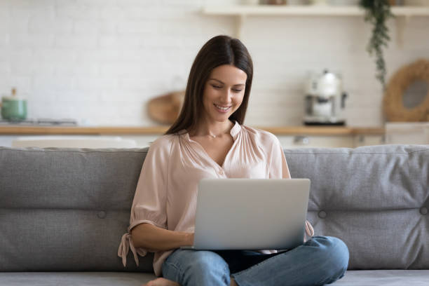 istock Woman looking at computer screen resting on couch at home 1171789086