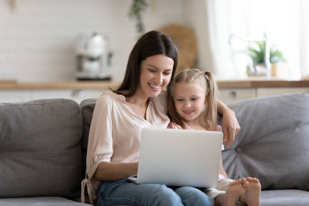 istock Young mother and preschooler daughter sitting on couch with notebook 1171789097