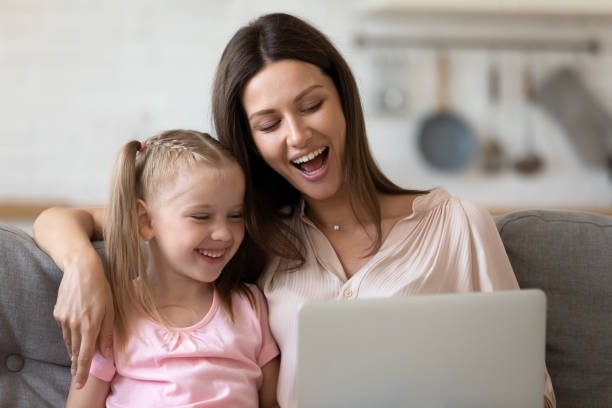 istock Mother and little daughter looking at computer screen enjoying cartoons 1171789100