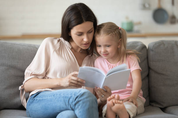 istock Mother and daughter sitting on couch reading a book 1171789153