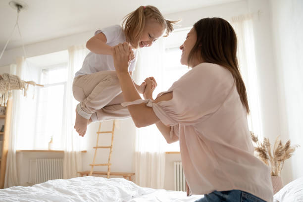 istock Active little girl jumping in bed holding mother hands 1171789209