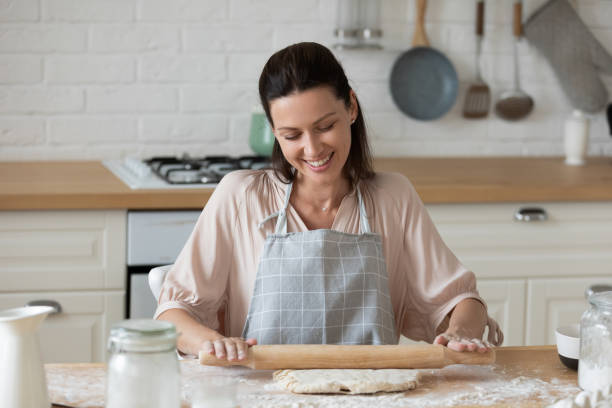 istock Woman flattening dough with rolling pin in the kitchen 1171789234