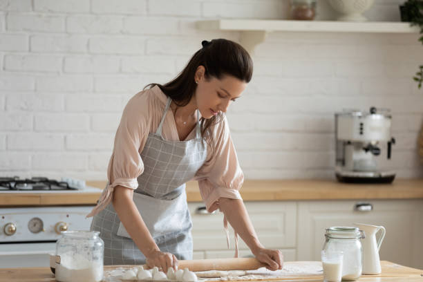 istock Housewife standing over kitchen table flattening dough with rolling pin 1171789237