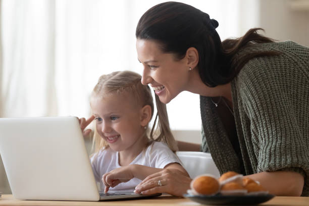 istock Mother daughter looking at laptop screen spend time in kitchen 1171789256