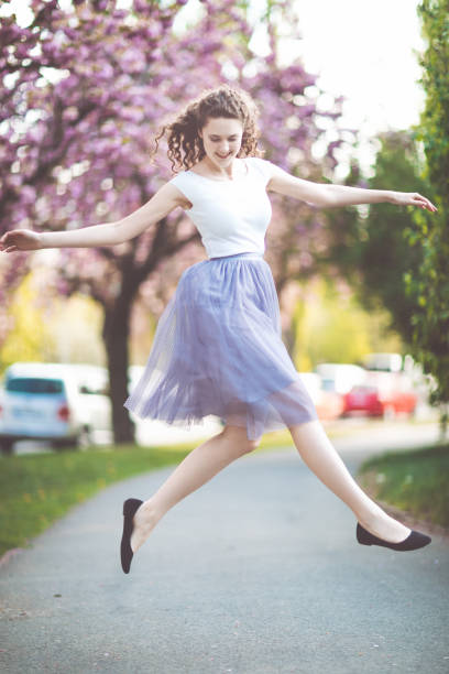 istock Young girl dancing and jumping under the blooming sakura trees. 1171791248