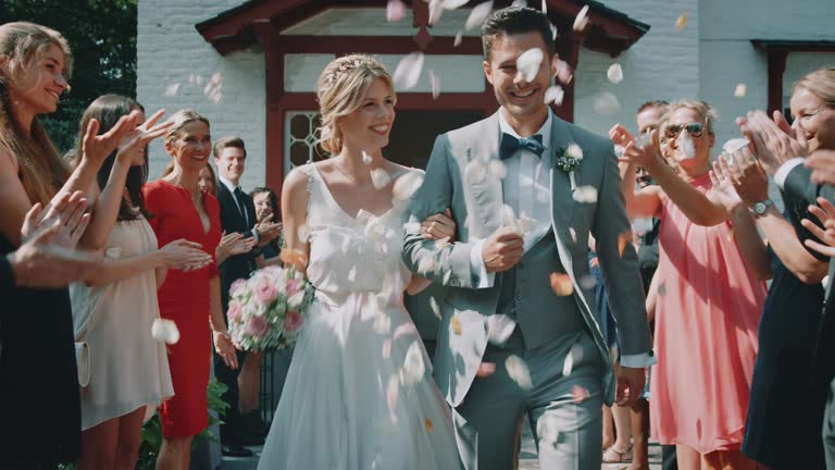 Guests throwing petals over couple outside church