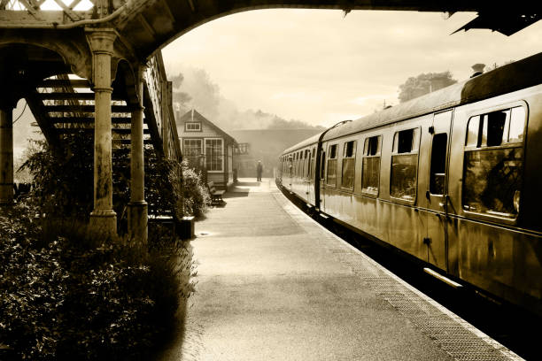Steam train at Sherringham Station, Norfolk, England, UK, black and white retrospective photograph of a steam train and carraiges at Weybourne station, Norfolk, England, UK, the platform is misty and in the distance is the gaurd and signal box train station black and white stock pictures, royalty-free photos & images