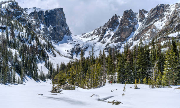 Spring Mountains - Spring view of a hiking trail along snow-covered Dream Lake towards Hallett Peak and Flattop Mountain in Rocky Mountain National Park, Colorado, USA. Estes Park, Colorado, USA - May 24, 2019: Lakes are still frozen. A few brave visitors hiking along snow-covered Dream Lake towards Hallett Peak and Flattop Mountain in Rocky Mountain National Park. hallett peak stock pictures, royalty-free photos & images