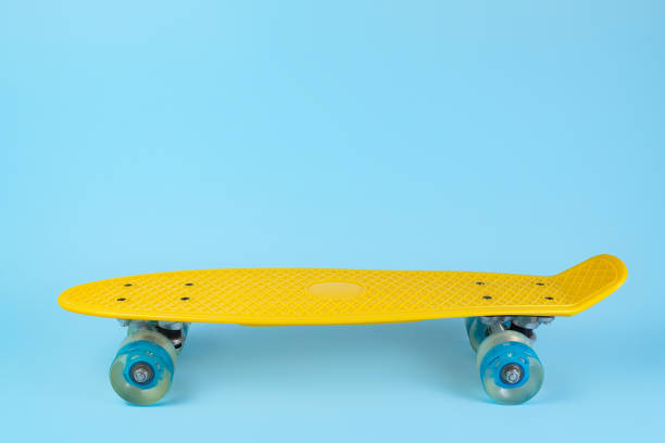 istock Photo yellow skateboard or pennyboard on blue background. Copy space. 1171805411