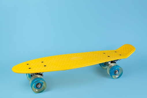 Photo yellow skateboard or pennyboard on blue background. Copy space