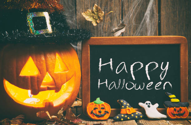 Halloween composition with chalkboard and gingerbread cookies on rustic wooden background