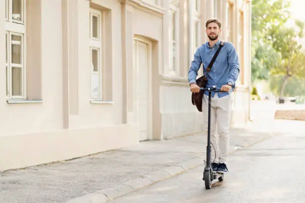 Young businessman riding an electric push scooter on his way to work.