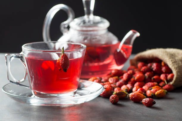 o copo de vidro de hip rosa secado do chá erval planta medicinal com frutas do rosa mosqueta no saco de serapilheira e no teapot de vidro na tabela rústica preta - dog rose - fotografias e filmes do acervo