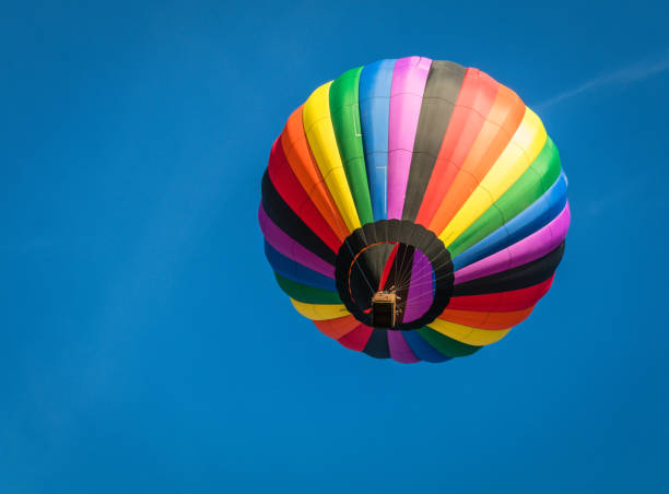 istock Rainbow colorful hot-air balloon floats over bright blue sky 1171817298