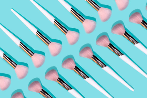 Pattern made of make up white brush on turquoise background.