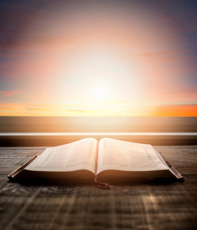 Primer plano de la Biblia abierta, con luz dramática. Mesa de madera con rayos de sol que vienen a través de la ventana. Imagen cristiana photo