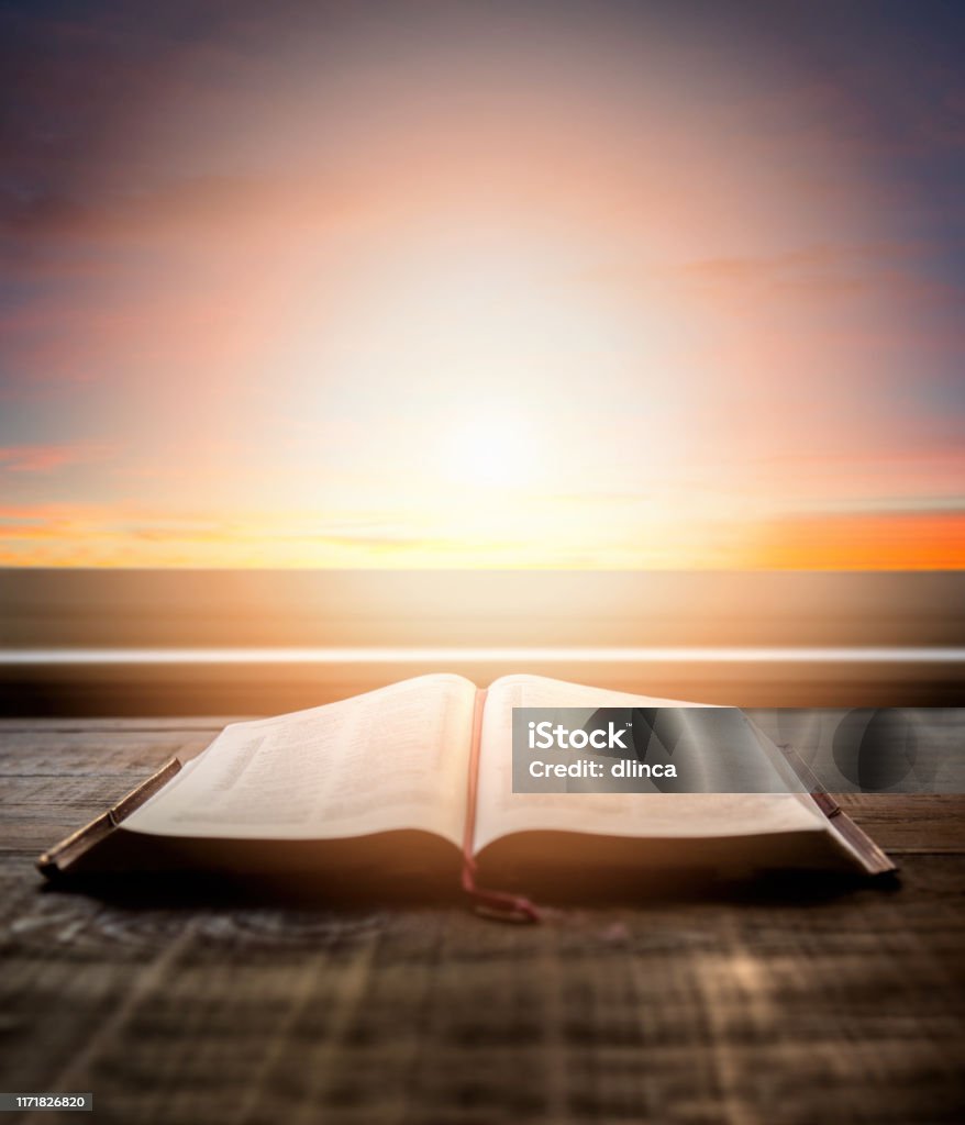 Close up of open Bible, with dramatic light. Wood table with sun rays coming through window. Christian image Close up open Bible, with dramatic light. Wood table with sun rays coming through window. Christian image Bible Stock Photo