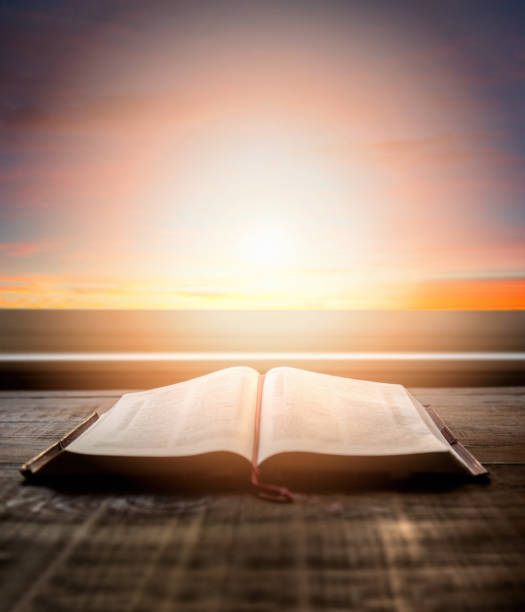 close up of open bible, with dramatic light. wood table with sun rays coming through window. christian image - belief in god imagens e fotografias de stock