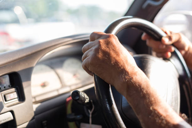 istock Men's hand holding the steering wheel with sunlight 1171830132