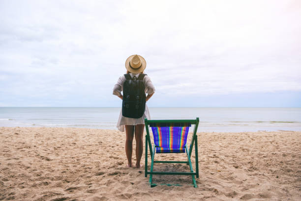 istock A female traveler with hat and backpack standing alone on the beach 1171841163