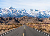 Highway heading toward Sierra Nevada mountains covered by snow.  California, USA