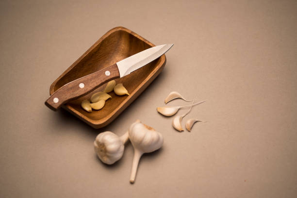 garlic and knife on a wooden plate with couple of peeled garlic pods - traditional culture asia indigenous culture india imagens e fotografias de stock