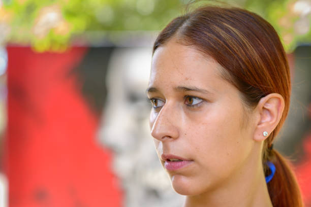 Serious thoughtful woman looking to the side watching something with interest outdoors in town in a close up head shot