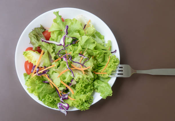 istock Green fresh vegetable salad on white place and brown table 1171855137