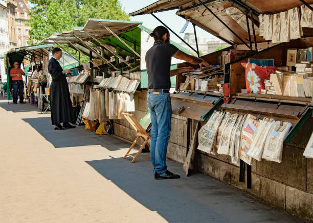 Priest at book stall along river Seine. Paris, France - July 04, 2017: A priest in cassock garment searches for a book at a pedestrian book stall by the river Seine. monsignor stock pictures, royalty-free photos & images