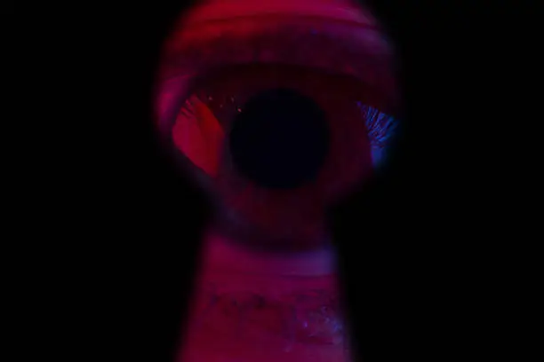 Human eye Looking through a keyhole. Halloweeen concept