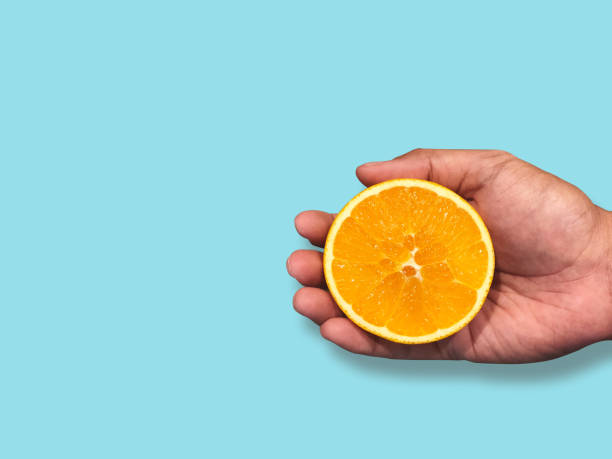 istock A man holding fresh ripe half orange fruit isolated on Blue pastel wall background. Smart Eat and Healthy Concept. copy space 1171859704