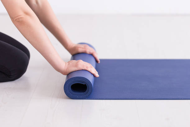istock Young girl in training outfit rolling up the blue mat. Selective focus 1171862242